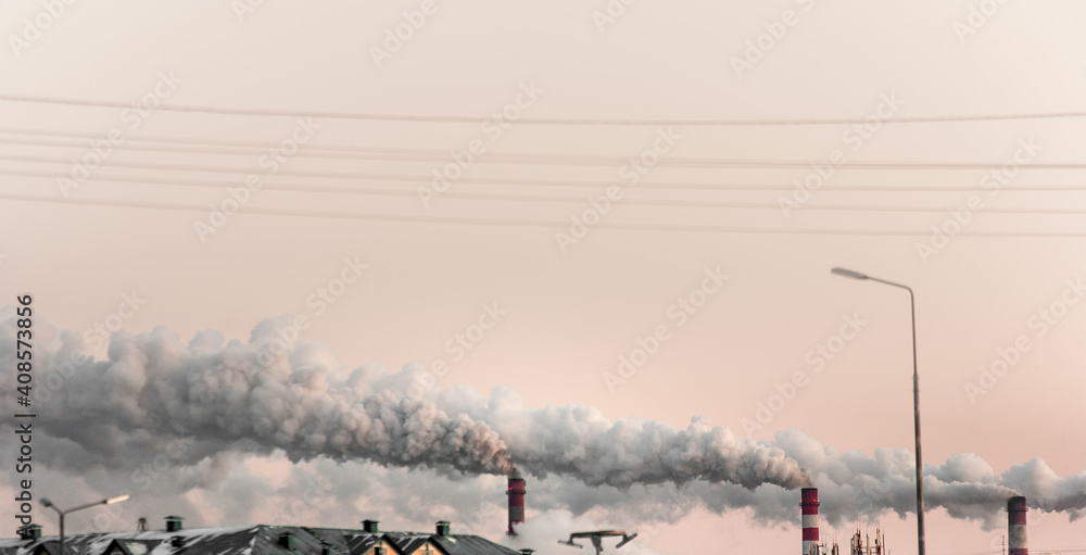 copy space with industrial chimneys with heavy smoke causing air pollution on the pink and gray smoky sky background