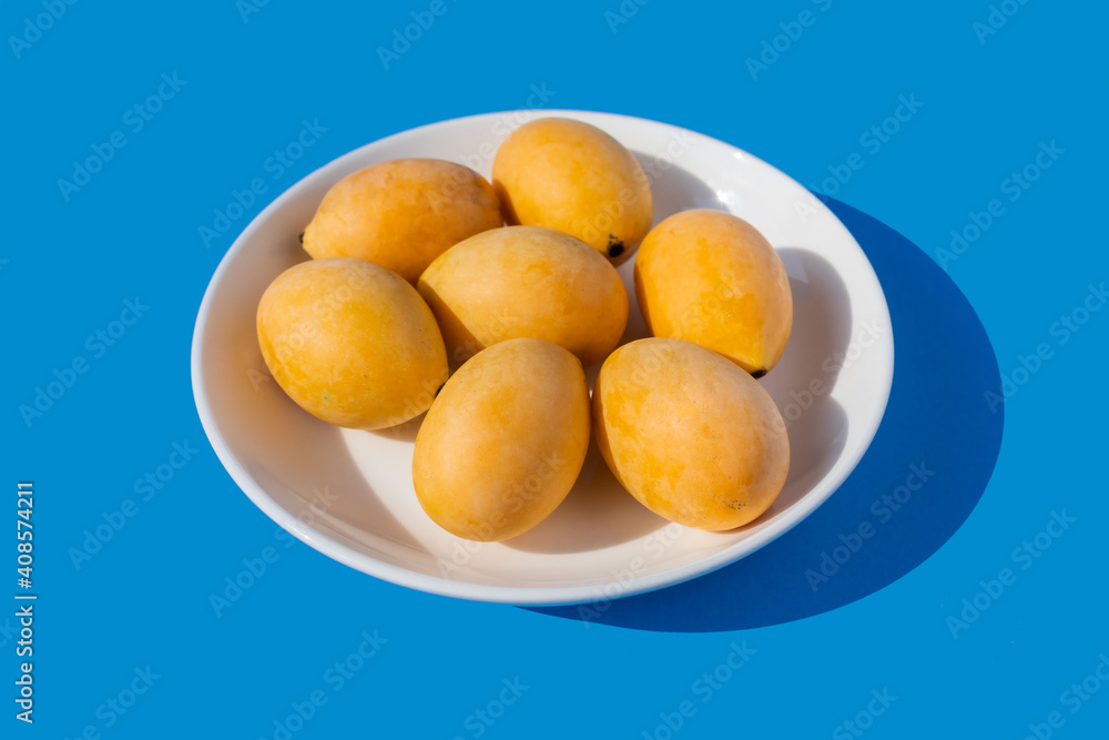 Sapodilla in white plate on the blue background.