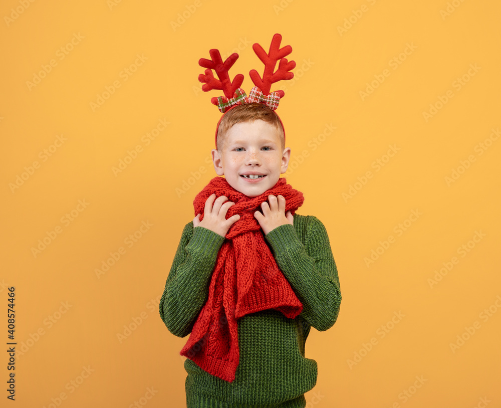 Cheerful kid in winter sweater and scarf posing on yellow Cheerful kid in winter sweater and scarf posing on yellow
