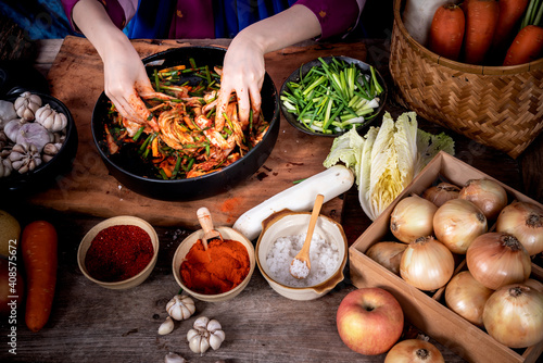 Photography Korean woman is wearing a traditional hanbok, she making Kimchi which is a fermented food preservation of Korean people consisting of many fresh vegetables and fruits, to food concept