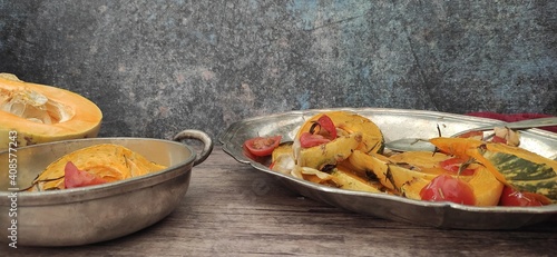 Roasted slices of pumpkin and cherry tomatoes on a silver tray