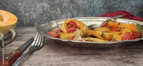 Roasted slices of pumpkin and cherry tomatoes on a silver tray