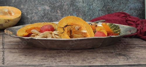 Roasted slices of pumpkin and cherry tomatoes on a silver tray