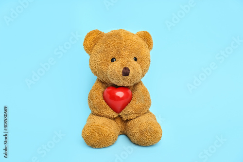 Cute teddy bear with red heart on light blue background. Valentine's day celebration