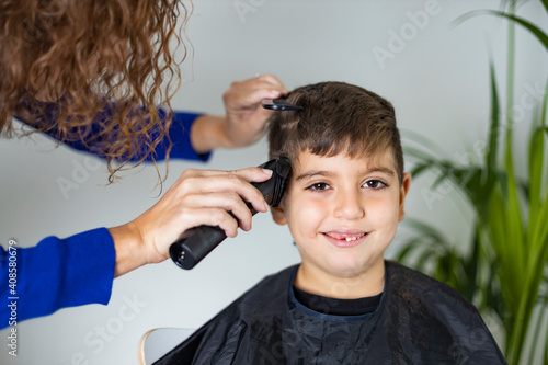 Mother cutting her son's hair at home