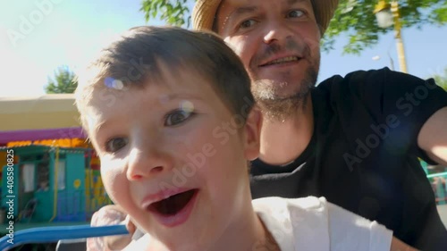 Selfie of father and son enjoying riding extreme roller coaster attraction in theme park rides or luna park. Close up smiling kid with happy dad in amusement park having fun on rollercoaster ride