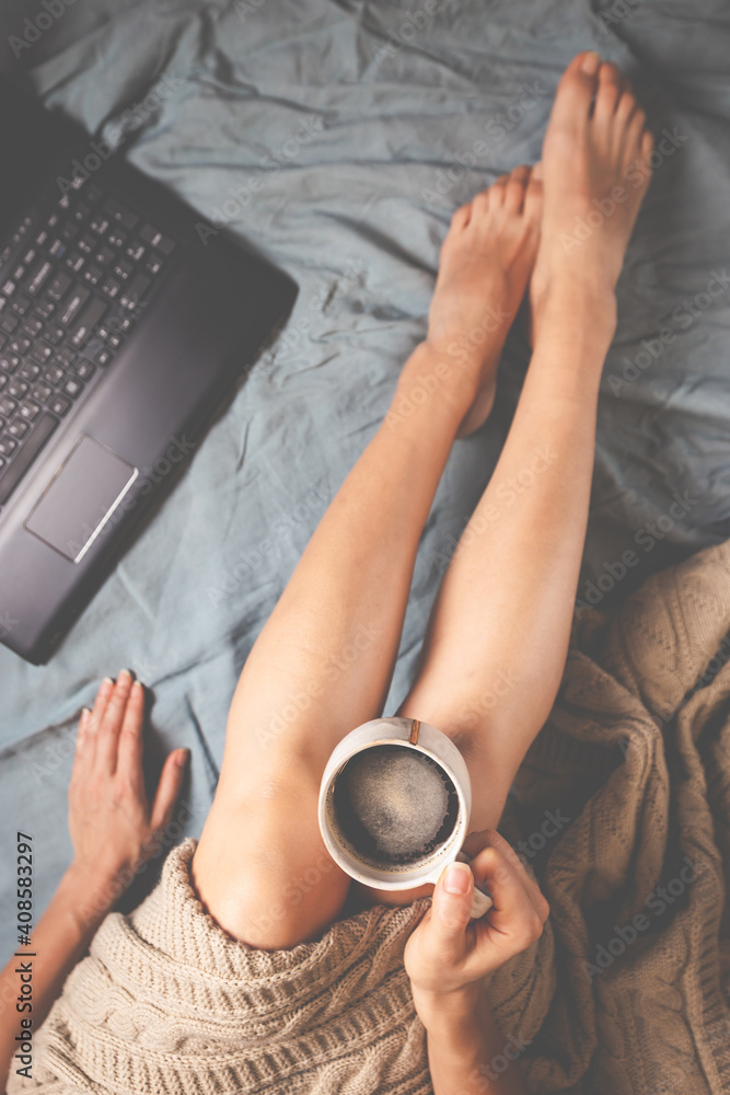 Young woman drinking coffee at home in her bed and checking her phone and laptop, top view, flat lay Young woman drinking coffee at home in her bed and checking her phone and laptop, top view, flat lay