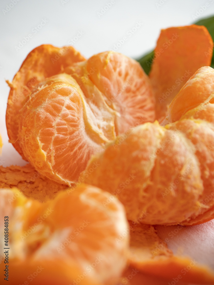 Fresh juicy bright orange tangerines with green leaves on a white cotton tablecloth in the morning light