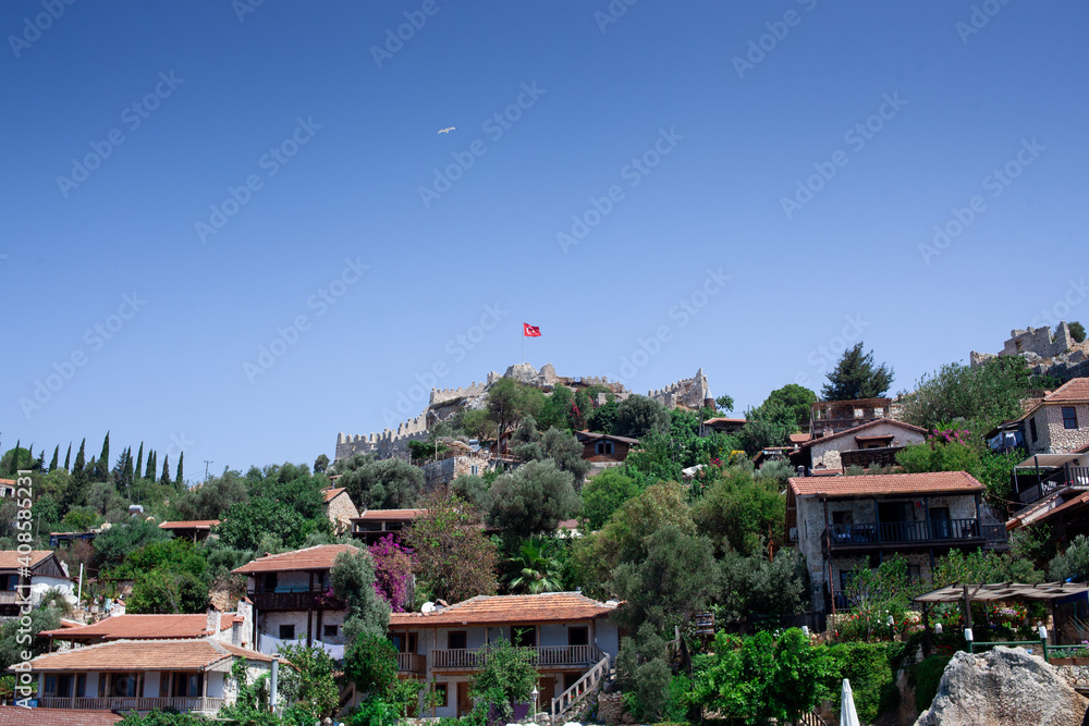 Simena island near ancient Demre and Kekova, Turkey. Buildings on the hill. turkish flag and seagull in the sky Simena island near ancient Demre and Kekova, Turkey. Buildings on the hill. turkish flag and seagull in the sky