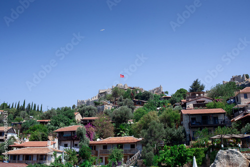 Simena island near ancient Demre and Kekova, Turkey. Buildings on the hill. turkish flag and seagull in the sky
