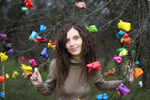 Woman between branches with paper origami tulips. Concept of waiting for spring after winter, bright colors in early spring time, women's day, 8 march, DIY. Selective focus.