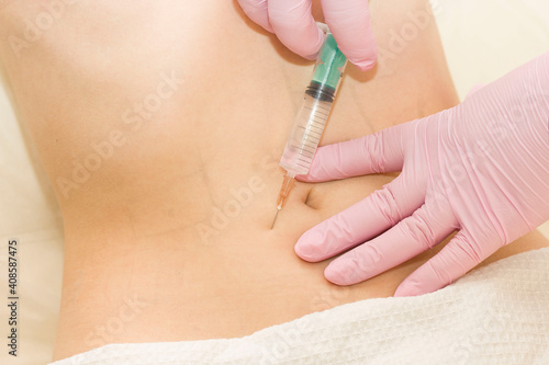 A shot in the stomach. A woman at a cosmetologist receives lipolytics in the stomach. Fat-burning