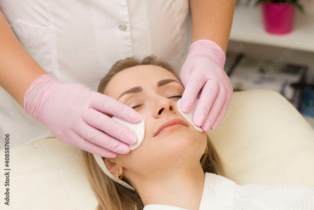 a young woman cleans her face with a sponge cosmetologist. Spa procedures. Relax a young woman cleans her face with a sponge cosmetologist. Spa procedures. Relax