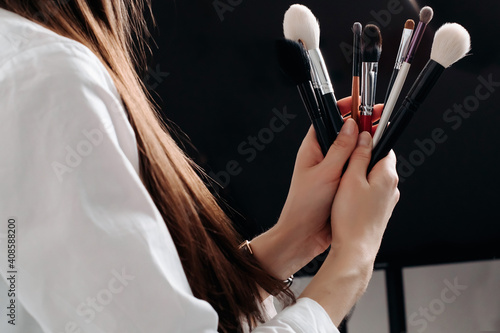 make-up artist's brushes in the hands of a close-up. on a light background