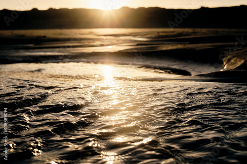 Small waves on the beach due to the changing of the tide during sunrise.