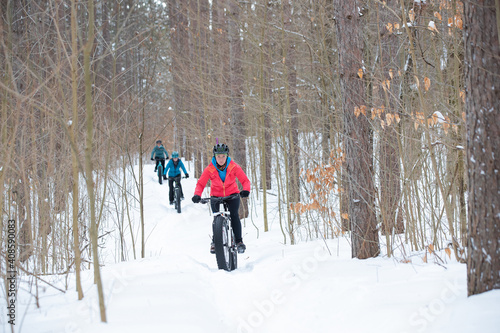 Obraz na płótnie Group of attractive women riding fat bikes in the snow w salonie