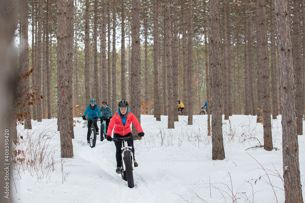 Group of attractive women riding fat bikes in the snow