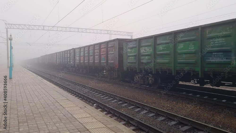 Cargo Train Moving On Platform Freight Train Passing Through Station. Wagons Rides On Steel Railway. Heavy Industry Transportation Concept. Cargo Train Moving On Platform Freight Train Passing Through Station. Wagons Rides On Steel Railway. Heavy Industry Transportation Concept.