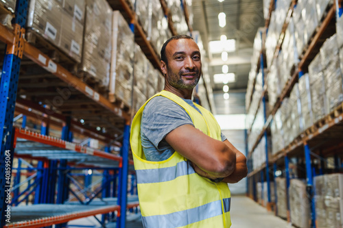 Obraz na plátně handsome warehouse worker wearing security vest posing arms crossed in a warehou