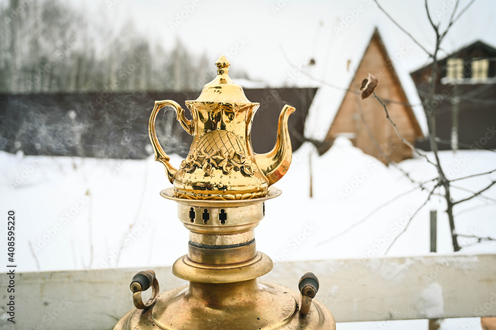 Obraz premium Beautiful golden teapot on heating samovar. Russian traditional tea machine. Private garden at winter.