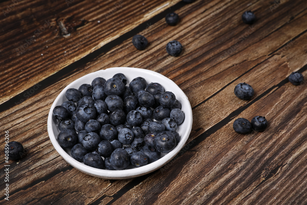 Top view of a white plate full of blueberries on a wooden table. Fruit vitamin. Top view of a white plate full of blueberries on a wooden table. Fruit vitamin.