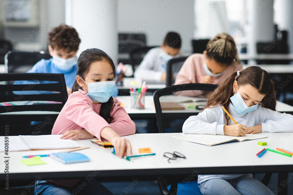 Children in masks sitting at desk in classroom Children in masks sitting at desk in classroom