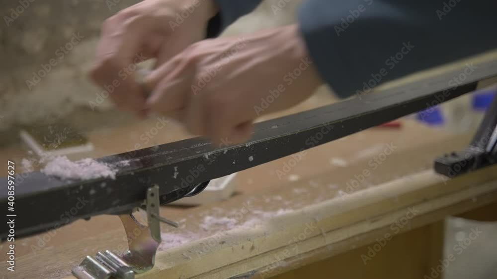 Scraping paraffin wax from ski during maintenance, slow motion Scraping paraffin wax from ski during maintenance, slow motion