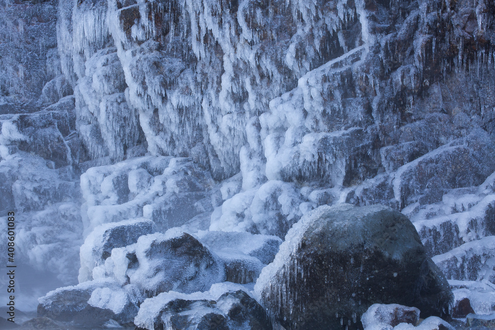 Giant rocks covered with a thick layer of ice and icicles in winter
