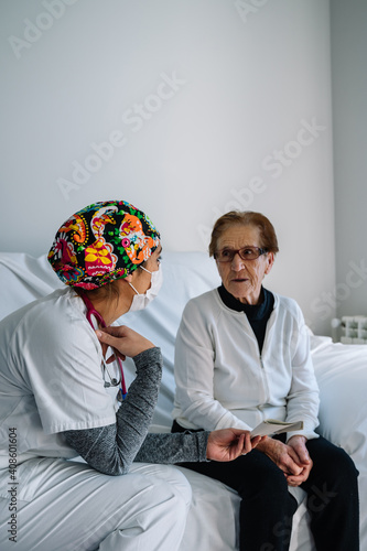 Nurse has a conversation with an elderly woman to reassure her after being checked.