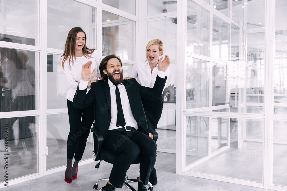 Happy colleagues are having fun together, rolling in an office c Happy colleagues are having fun together, rolling in an office c