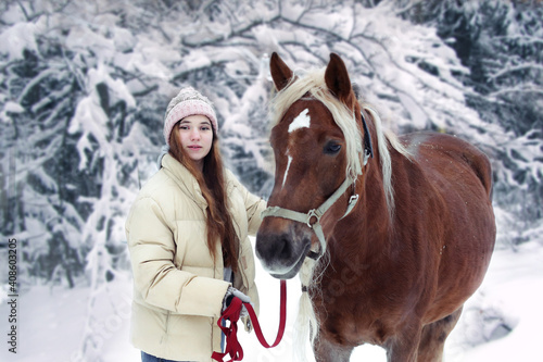 girl with long brown hair and chestnut horse with plaited mane close up portrait on winter snowy background