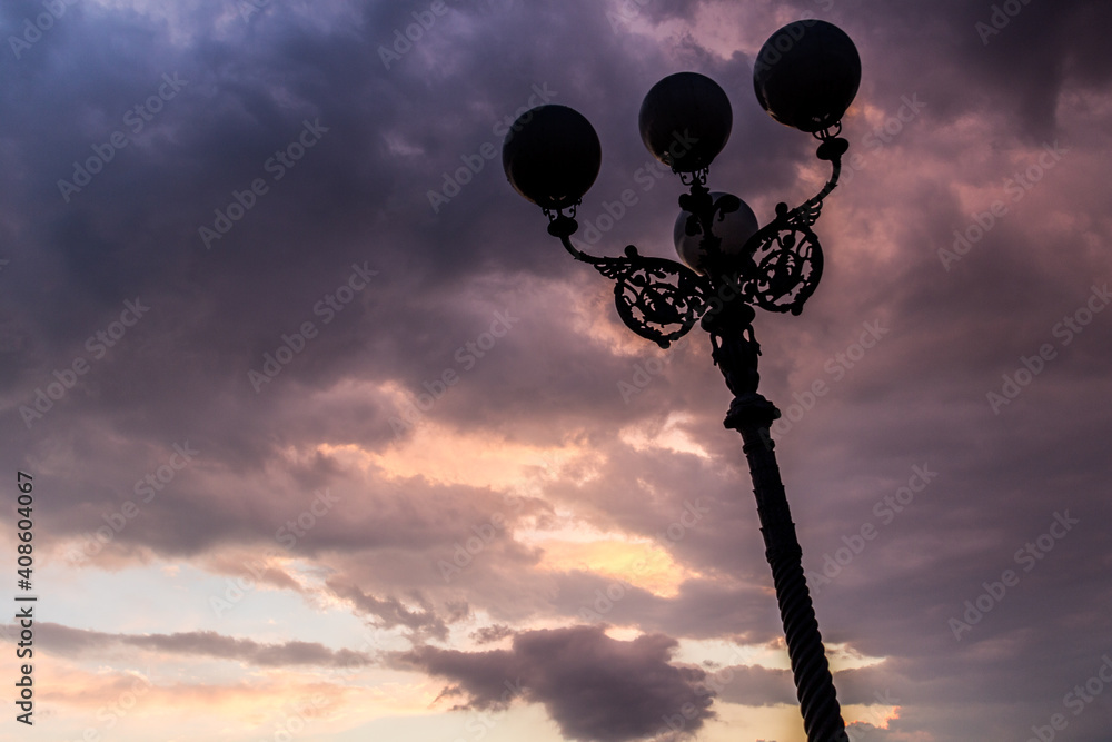Silhouette of a historical street lamp on a background of clouds
