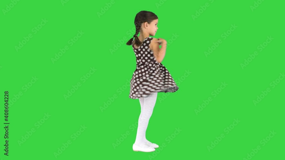 Smiling little girl posing and twirling her polka dot dress on a Green Screen, Chroma Key. Smiling little girl posing and twirling her polka dot dress on a Green Screen, Chroma Key.
