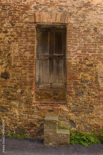Fototapeta Naklejka Na Ścianę i Meble -  An old wooden door in a disused residential building in the historic centre of the medieval town of Monticiano in Siena Province, Tuscany, Italy
