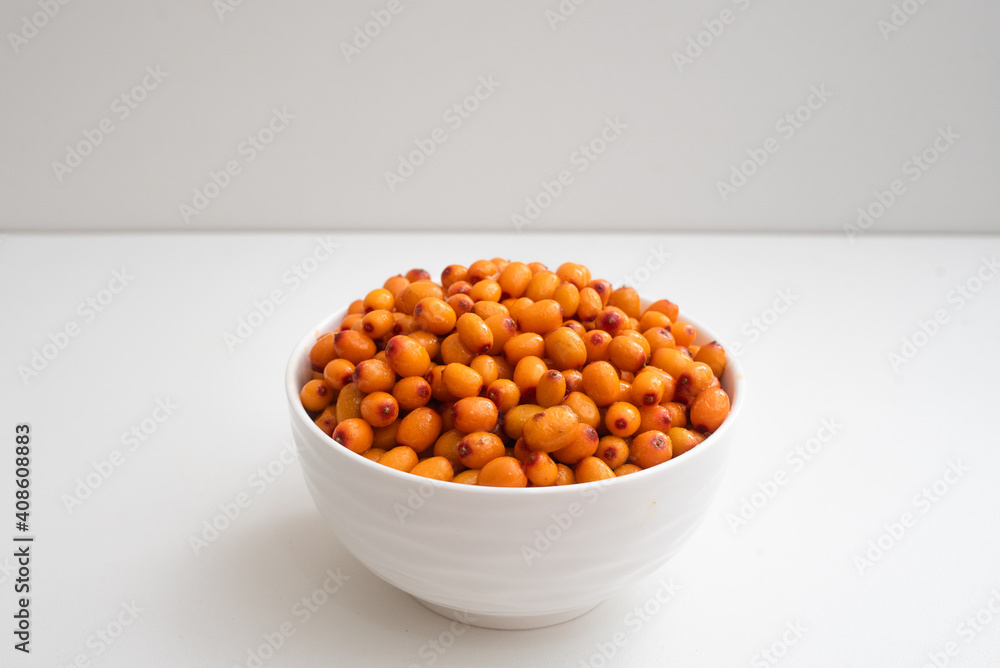 Deep white plate with sea buckthorn berries. Side view. On a two-tone background. Deep white plate with sea buckthorn berries. Side view. On a two-tone background.