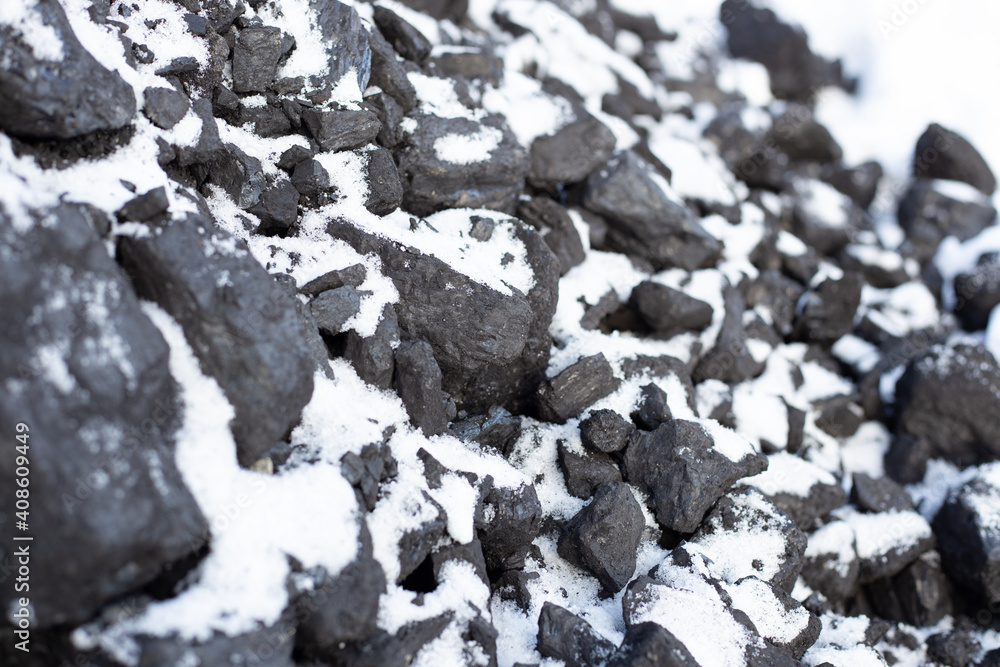 large pieces of coal under the snow. Fuel for the stove in winter. Heating a house in the countryside