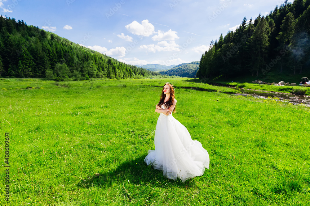 A beautiful curly-haired bride in a long lace white dress is wal A beautiful curly-haired bride in a long lace white dress is wal