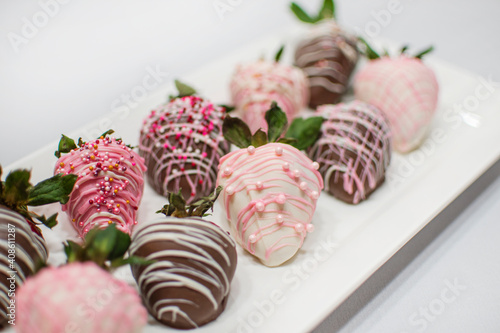Close up mix strawberry covered chocolate on white plate on white background