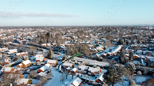 Snowy rooftops, railway track and bridge in snow covered British town, aerial drone