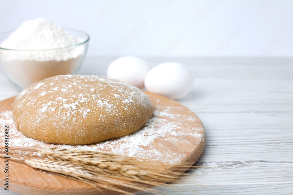 Dough and ingredients for its preparation: flour and eggs on white wooden background. Close-up. Copy space. Dough and ingredients for its preparation: flour and eggs on white wooden background. Close-up. Copy space.