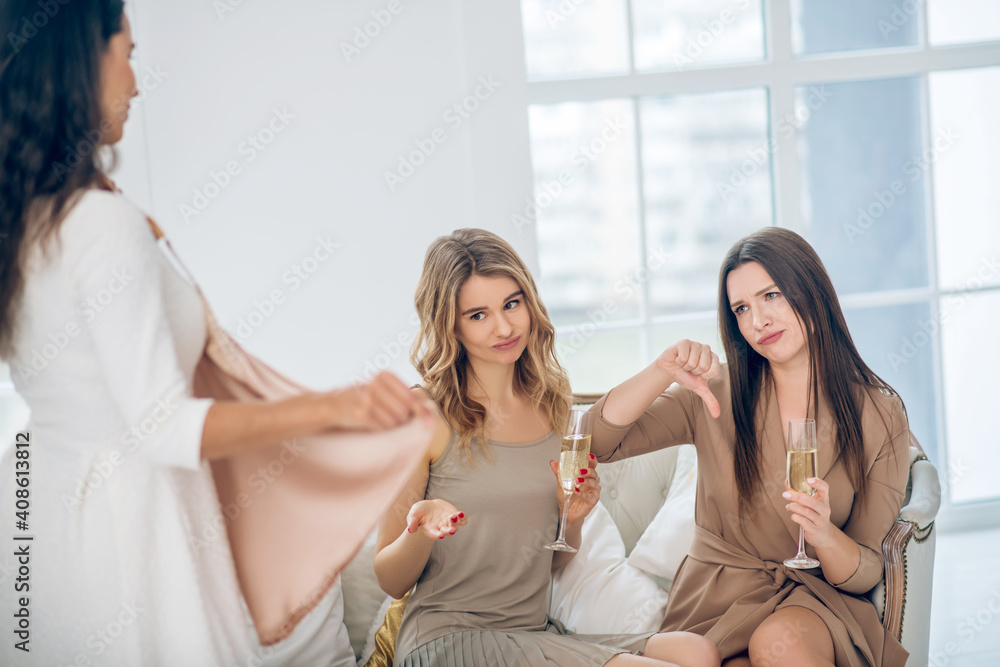Three beautiful girls choosing a dress and looking uncertain