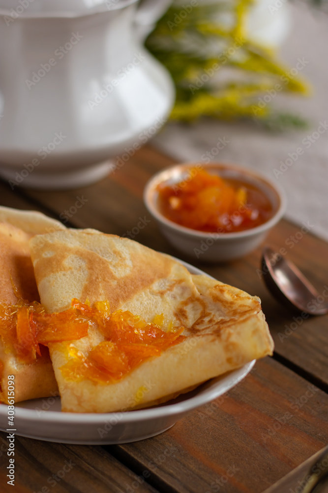 Thin pancakes with orange jam or marmalade on wooden background. Tasty breakfast. Maslenitsa. Thin pancakes with orange jam or marmalade on wooden background. Tasty breakfast. Maslenitsa.