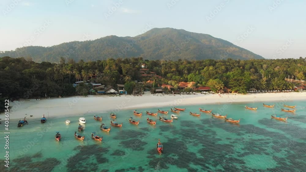 Aerial drone shot of traditional thai longtail boats by the coast with reef in the foreground and mountains in the background. Crystal clear shallow water during summer sunny sunset golden hour. POI Aerial drone shot of traditional thai longtail boats by the coast with reef in the foreground and mountains in the background. Crystal clear shallow water during summer sunny sunset golden hour. POI