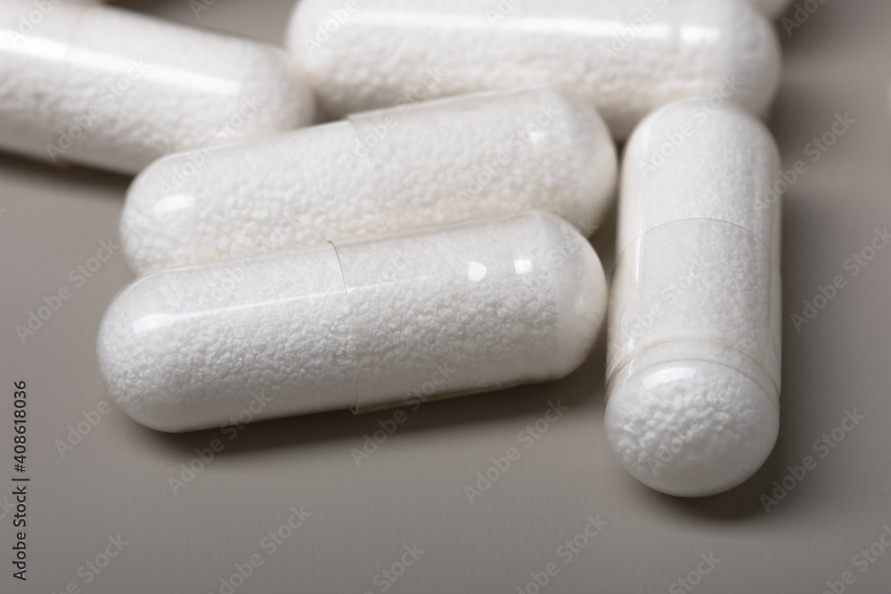 White medicine capsules on a gray background. Shallow depth of field White medicine capsules on a gray background. Shallow depth of field
