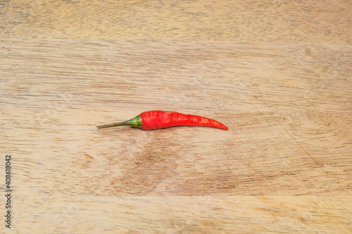 One red chili pepper on wooden background. Top view.