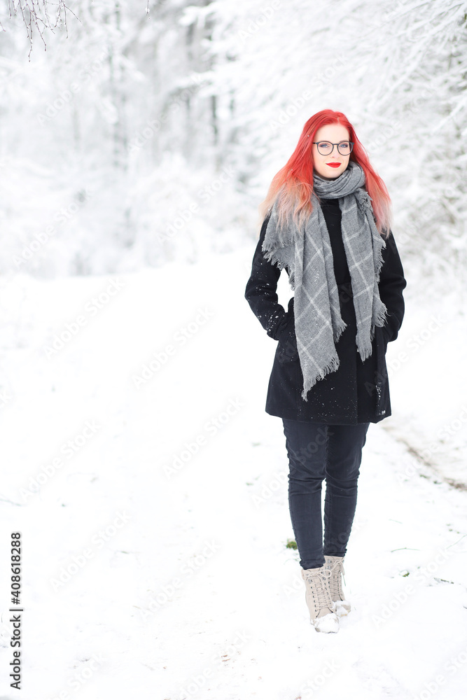 Attractive red hair girl is walking in snowy nature smiling at the camera. Vertically. Attractive red hair girl is walking in snowy nature smiling at the camera. Vertically.