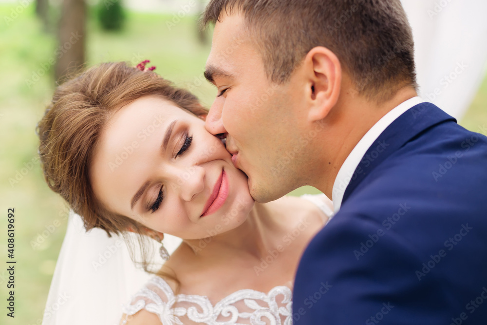 lovely couple. wedding day of the bride and groom. newlyweds on a walk. The man gently kisses the girl on the cheek. lovely couple. wedding day of the bride and groom. newlyweds on a walk. The man gently kisses the girl on the cheek.