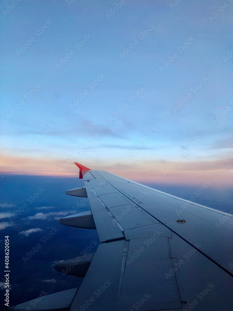 Fototapeta premium Sky and sunset from the plane window. Airplane wing. Open borders High quality photo Vertical mobile photo End of the pandemic. Travel to Europe and the world 