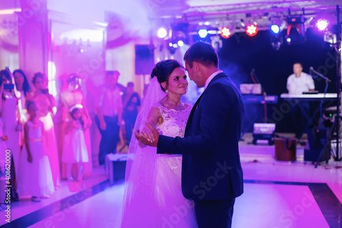 Young beautiful couple dancing in a restaurant celebrating a wedding. a woman in a white long dress, a man in a suit.