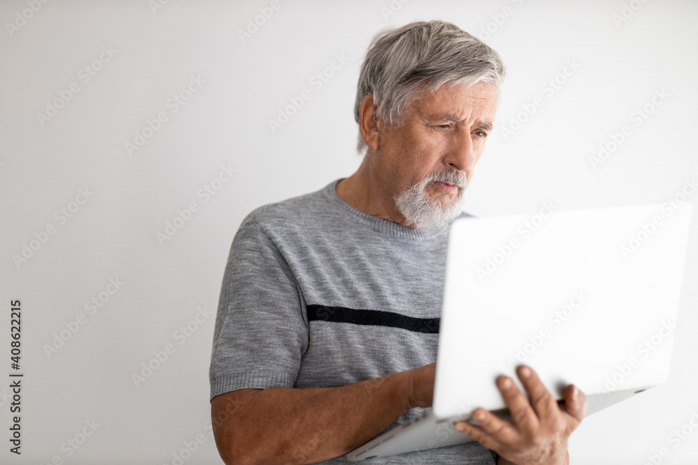 Senior man using a laptop computer at home, struggling with techology a bit, shopping online during COVID confinement/lockdown/quarantine Senior man using a laptop computer at home, struggling with techology a bit, shopping online during COVID confinement/lockdown/quarantine